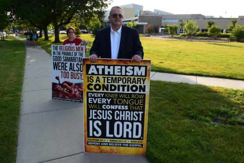 Demonstrators hold signs  on Aurora avenue on the sidewalk in front of the main entrance at Naperville Central. 