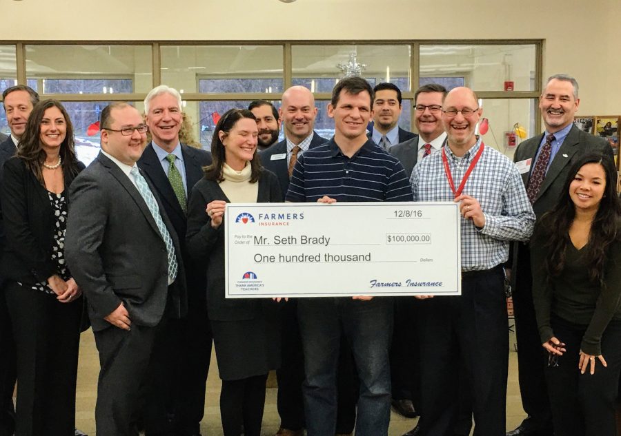 Social studies teachers Seth Brady and Randy Smith hold a check for $100,000 presented by Farmers Insurance. The money will be used to fund Brady's Global Scholar initiative in Illinois. The program has also received state legislative support.