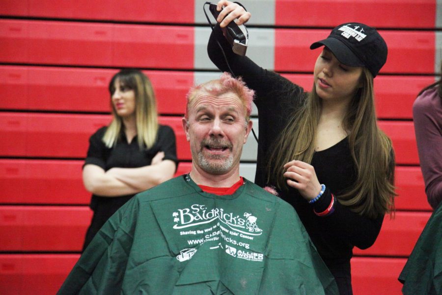 Senior Mary Amato shaves social studies teacher Todd Holmberg’s head. Each year, he asks his classes to raise money for St. Baldrick’s. Students bring in money to enter a raffle for the chance to shave his head.
