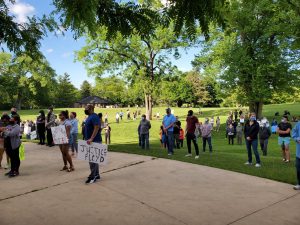 People sprawled throughout the green hold signs protesting the brutal police violence.