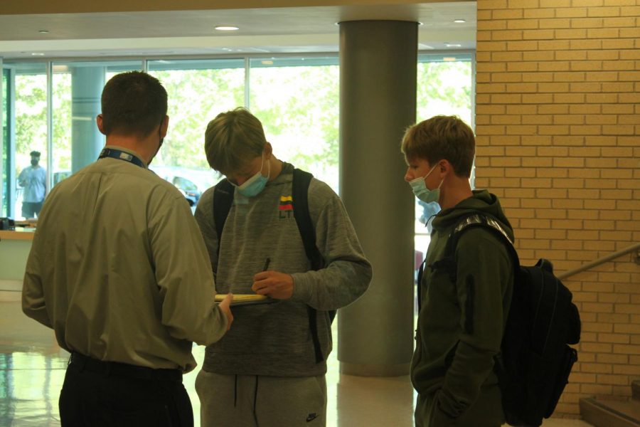 Dean Pete Flaherty signs out students rushing out of  Naperville Central in the wake of a threat message circulating the school on Monday, Oct. 18. 