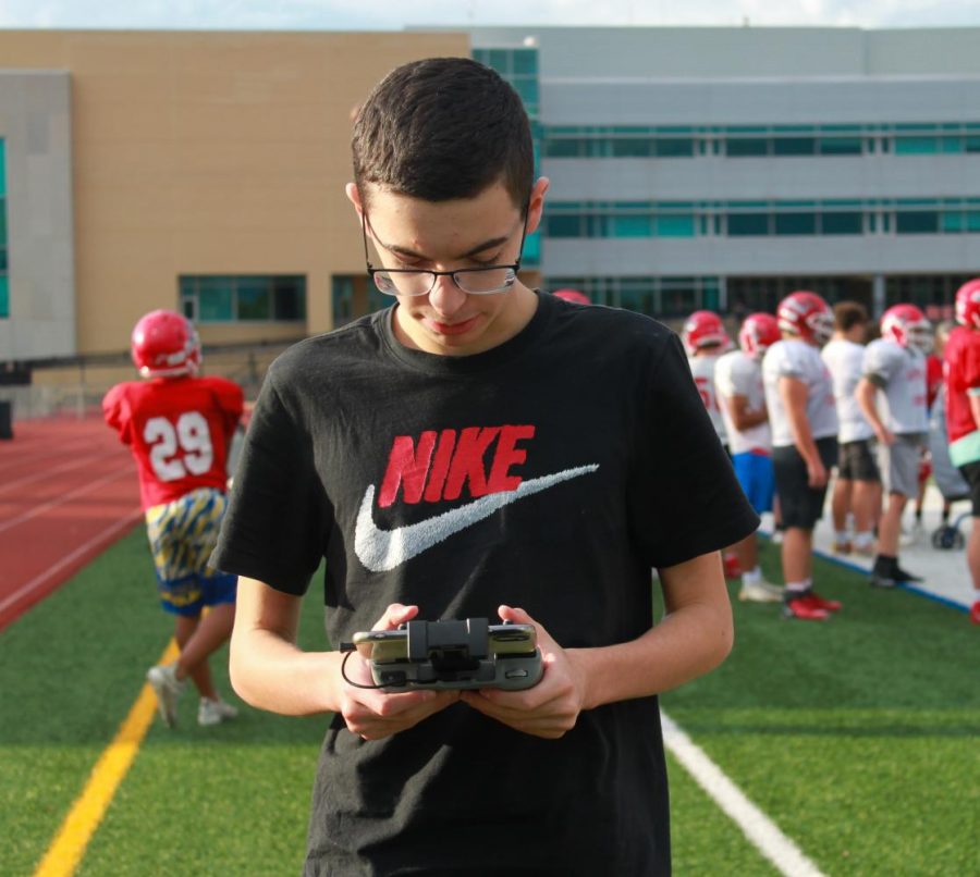 Garron Donovan flies his drone on Naperville Central's stadium field during varsity football game. 
