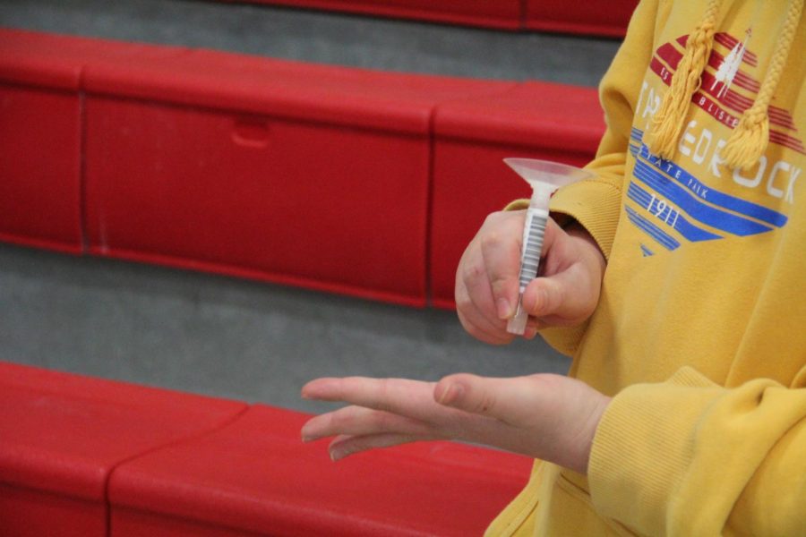 Freshman Jason Henrikson taps the test tube on his hand to move the spit sample through the funnel while SHIELD testing at Naperville Central on Dec. 6.