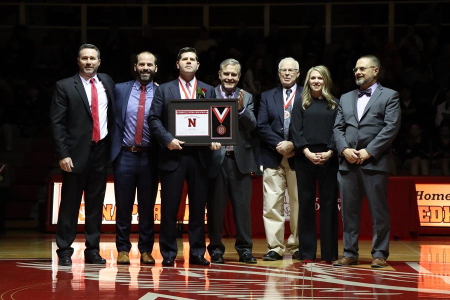 8: Mike Haverty holds his Athletic Hall of Fame plaque after receiving it on Feb. 3.  
The lighting in this shot created a powerful dynamic where the figures stand out dramatically,  even in the middle of a crowded gym at halftime of a crosstown basketball match.