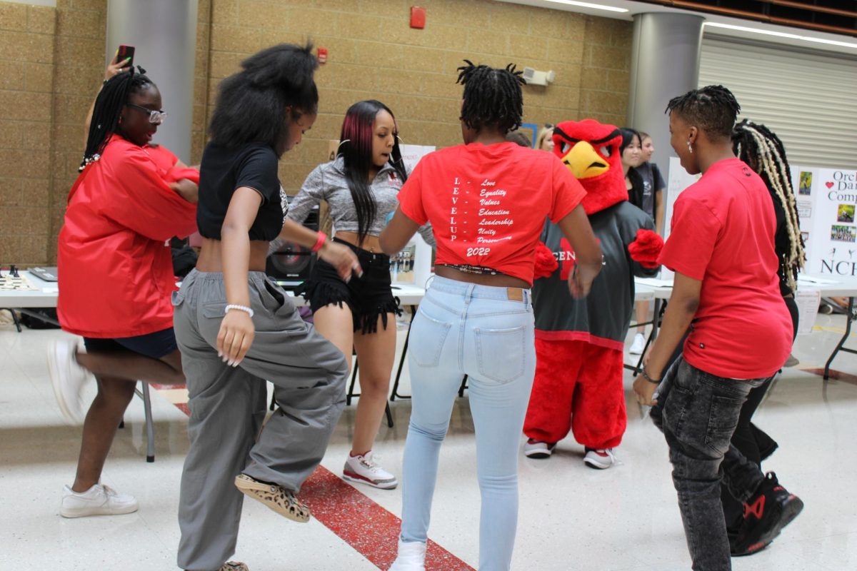Members of the Dynasty Steps Team show off their moves with Central's mascot Rocky the Redhawk at the Club Expo at Central's Red and White Night.