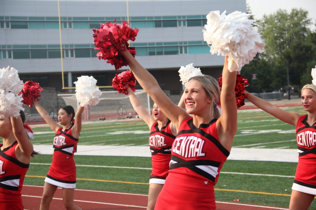 Cheer team member and junior Claire Poulaki waves to the student section during varsity footballs scrimage at Centrals Red and White Night.