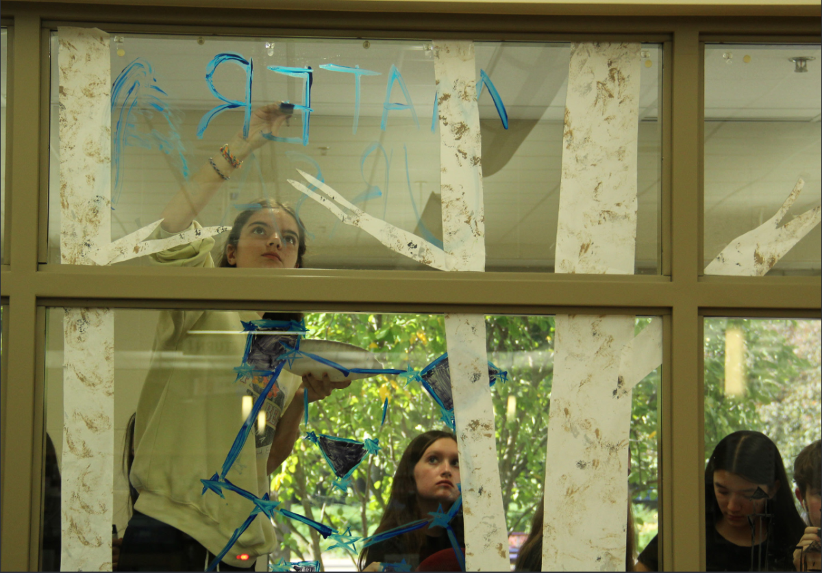 Senior Isabel Deer paints the windows in front of Central's Learning Commons for Latin Club's homecoming decorations on Sep. 29.