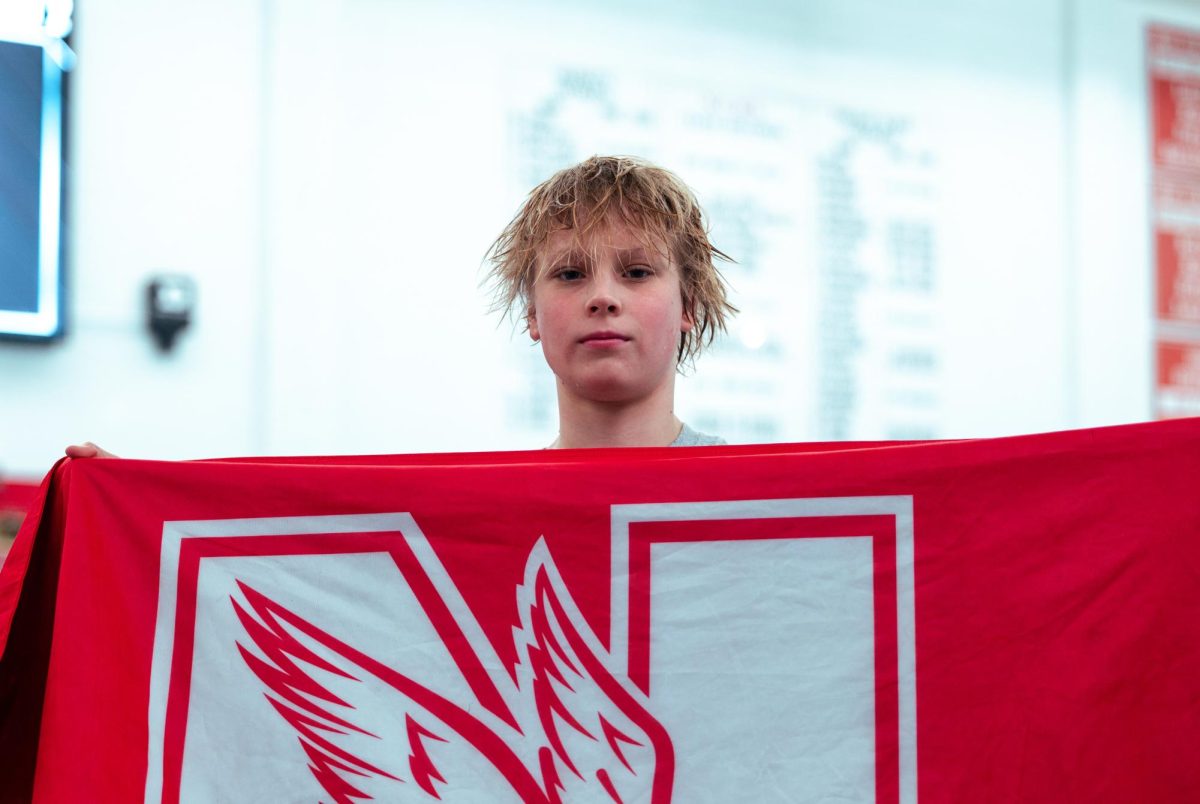 Freshman Alex Beiga holds a Central flag at the DuPage Valley Conference boys swim and dive championship on Feb. 3. Beiga was killed in a ski accident on April 1 in Switzerland. Photo courtesy of NCHS Swim and Dive.
