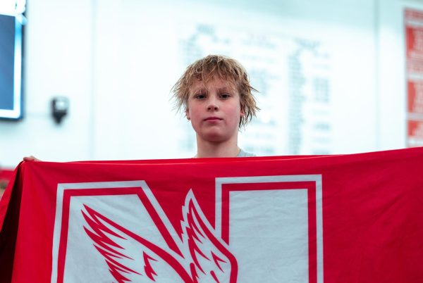 Freshman Alex Beiga holds a Central flag at the DuPage Valley Conference boys swim and dive championship on Feb. 3. Beiga was killed in a ski accident on April 1 in Switzerland. Photo courtesy of NCHS Swim and Dive.