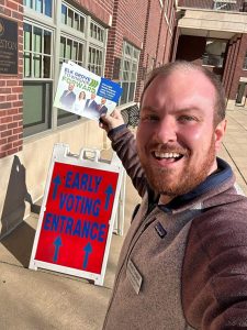 Social Studies teacher Robert Lugiai poses in front of an early voting location for a selfie. Lugiai was elected as part of a slate of Democrat candidates in the April 1 election. (Photo courtesy of Robert Lugiai)