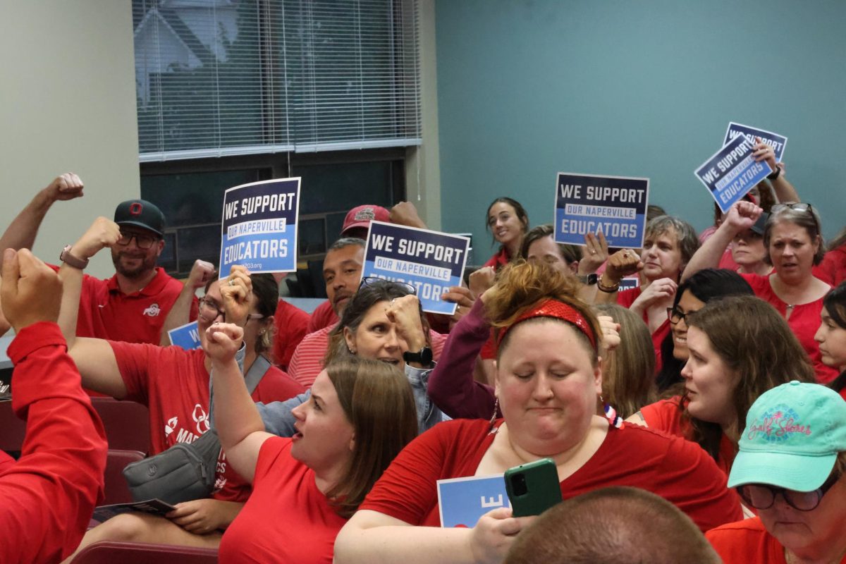 District 203's educators and community hold up signs at a school board meeting on Aug. 18. The signs read "We support our Naperville Educators". 