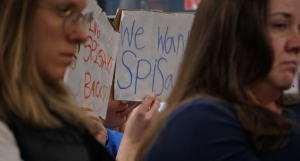 Kennedy Middle School students hold up signs supporting their teacher, Mr. Spisak. Dozens of students spoke during public comment about connections they've built with influential teachers on the RIF list, some of which also include Central's Maria Connell and North's Will DeBolt.