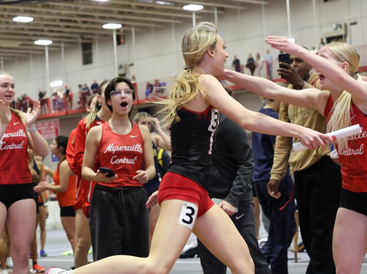 After a strong finishing kick, junior Mckenzie Gettamy celebrates a hard-earned 4x200m relay victory alongside her team. (Photo Credit: Kelley Burke via https://sites.google.com/naperville203.org/nchstrackxc)